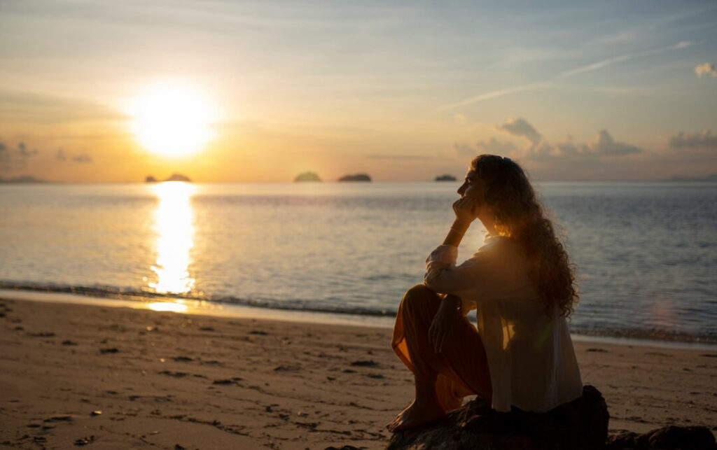 Woman on the beach looking out and in deep thought.