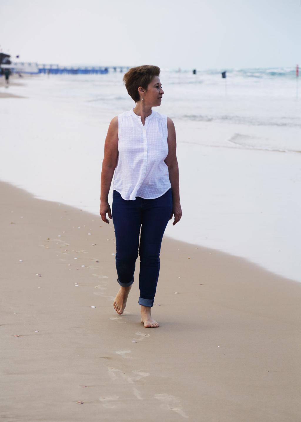 A woman walking barefoot along the shoreline on a quiet beach
